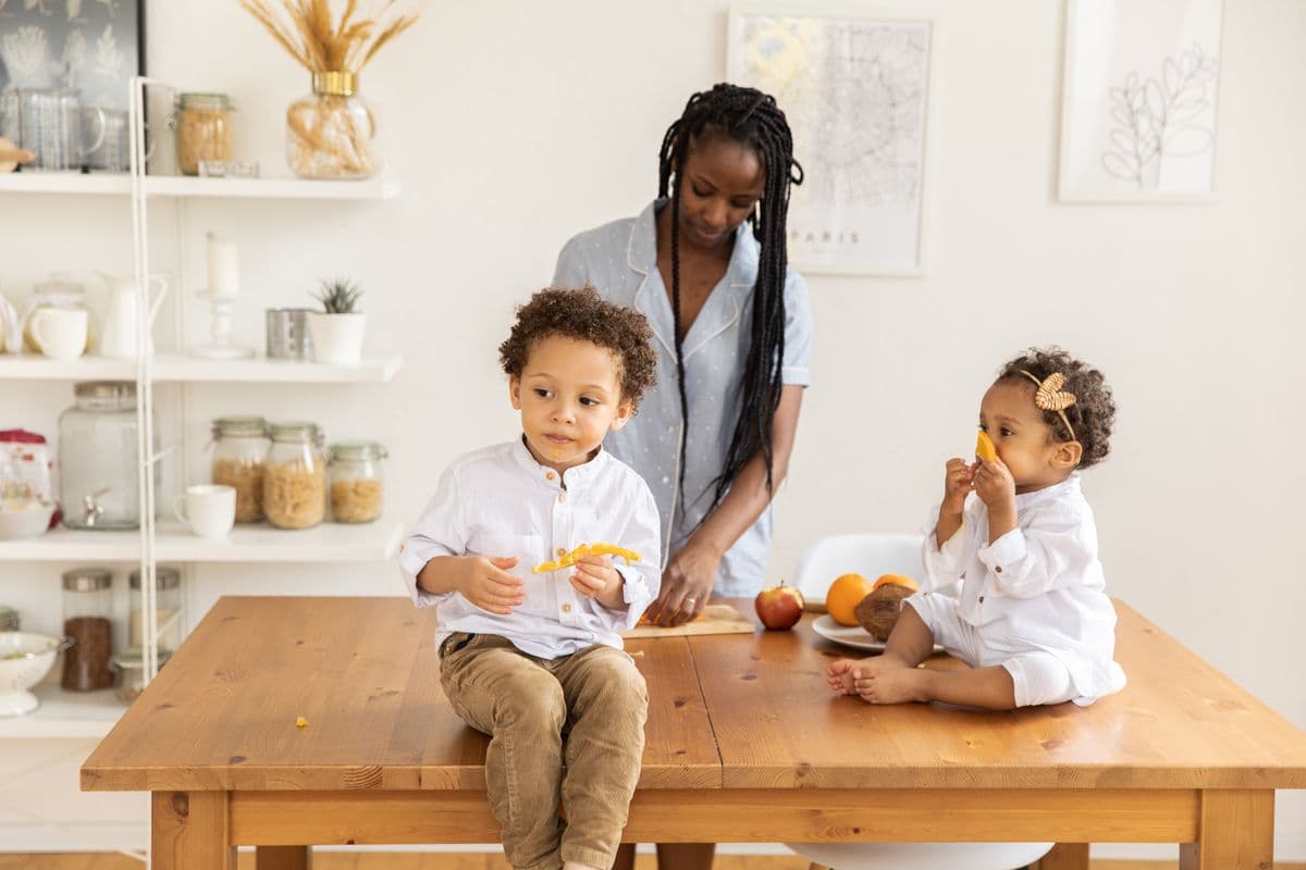 A mother with two toddlers at a kitchen table
