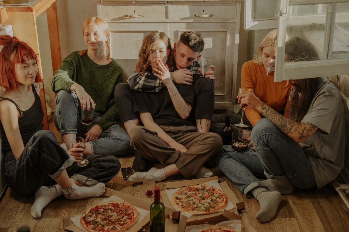 Young adults sharing pizza on a living-room floor