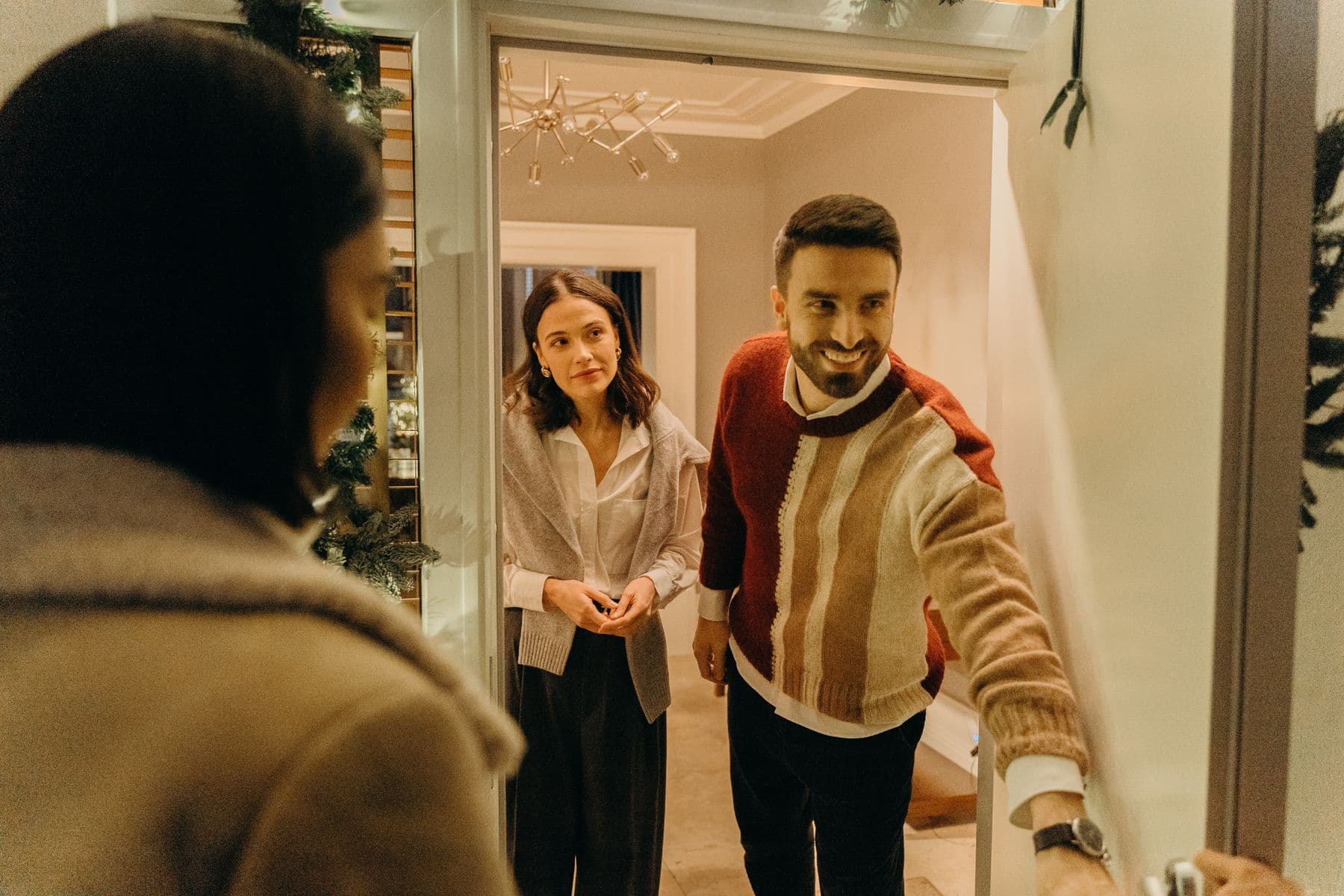 A couple welcoming a guest at their front door