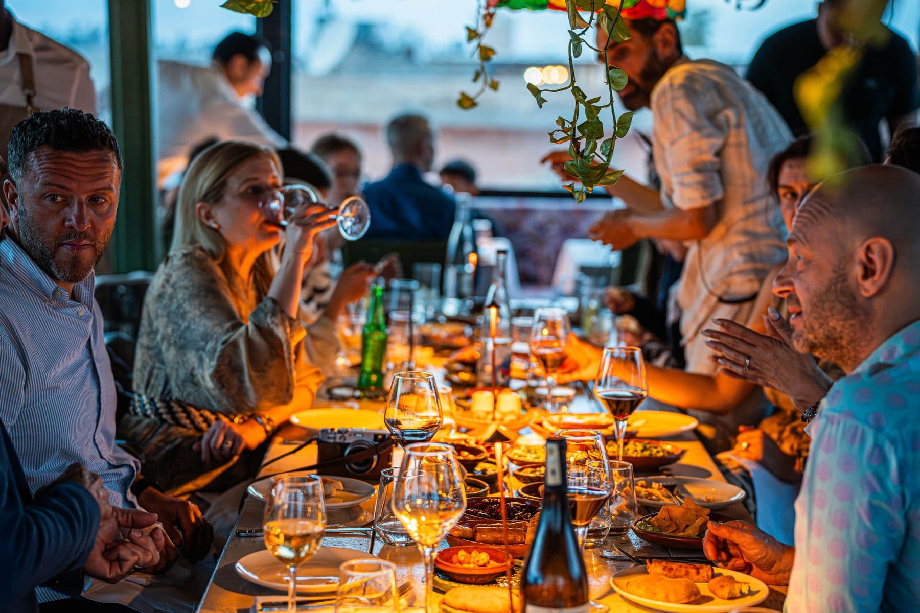 A group of friends at a long candlelit restaurant table