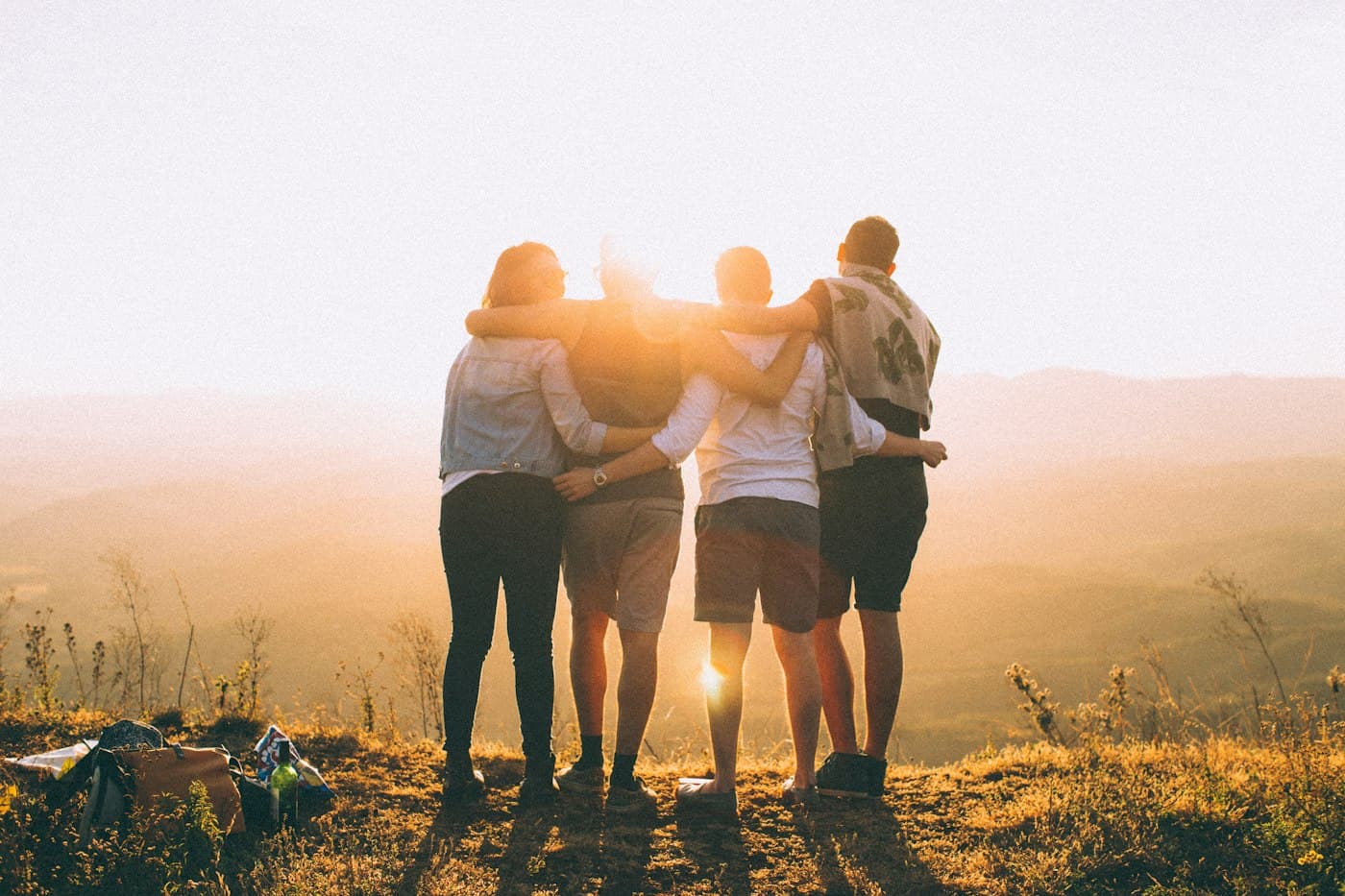 Friends standing together on a hillside at sunset