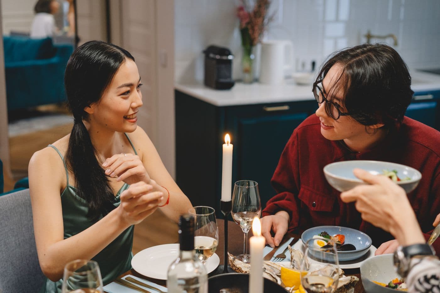 Friends talking over dinner at a candlelit table